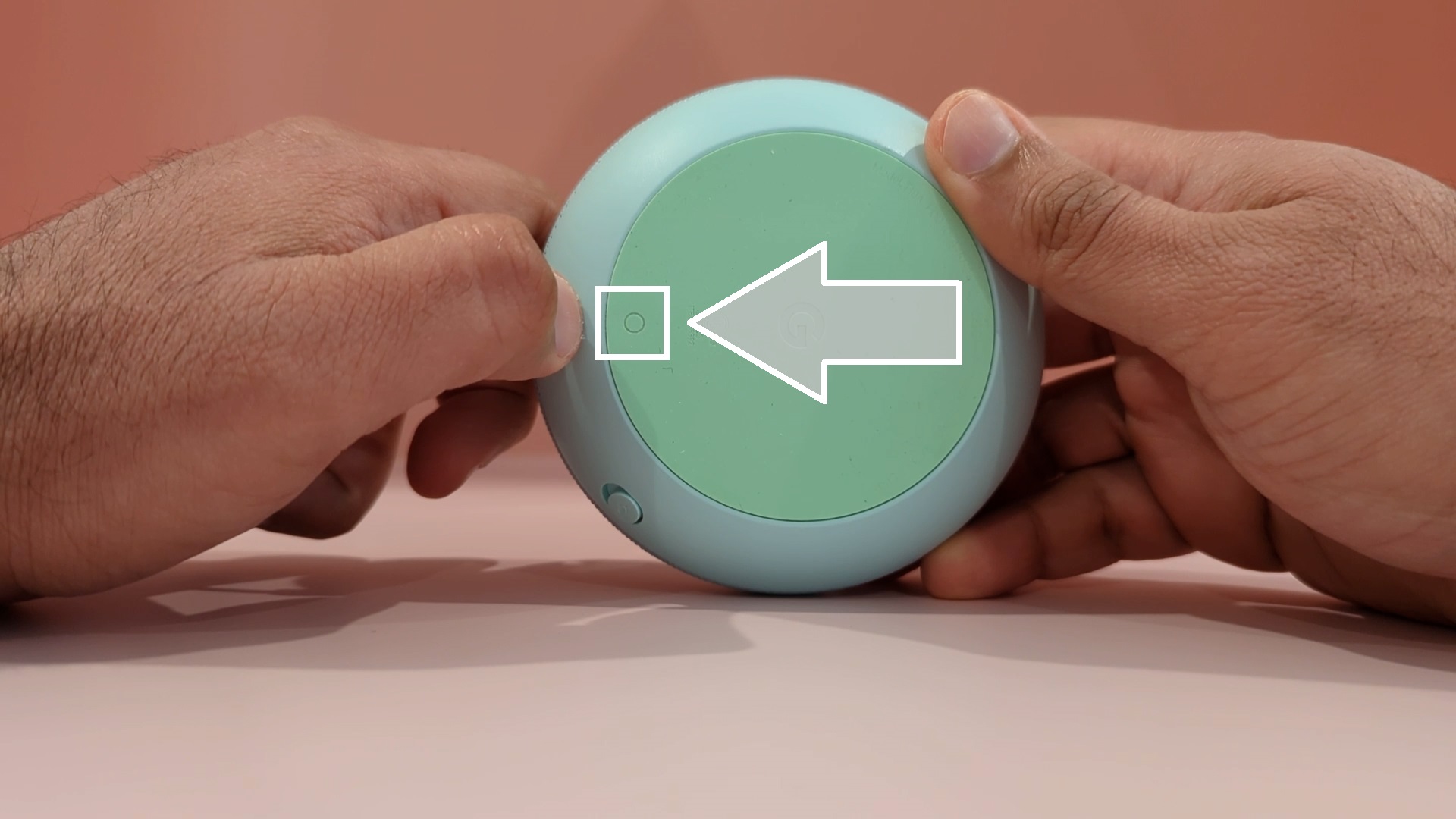 To reset your Google Nest Mini, first remove the power cord from your device and then invert it. 
Near the power cord slot, locate the small circular reset button as shown in the image.